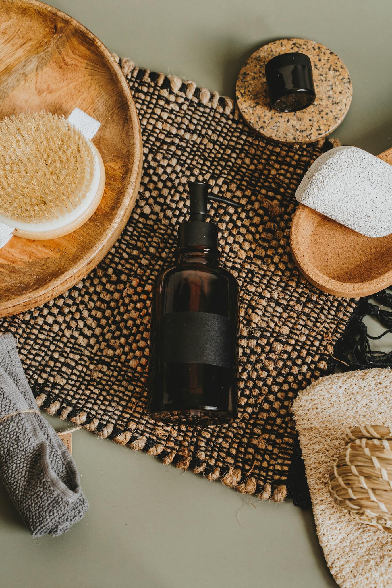 Flat lay of natural skincare products and accessories on woven mat for body care.
